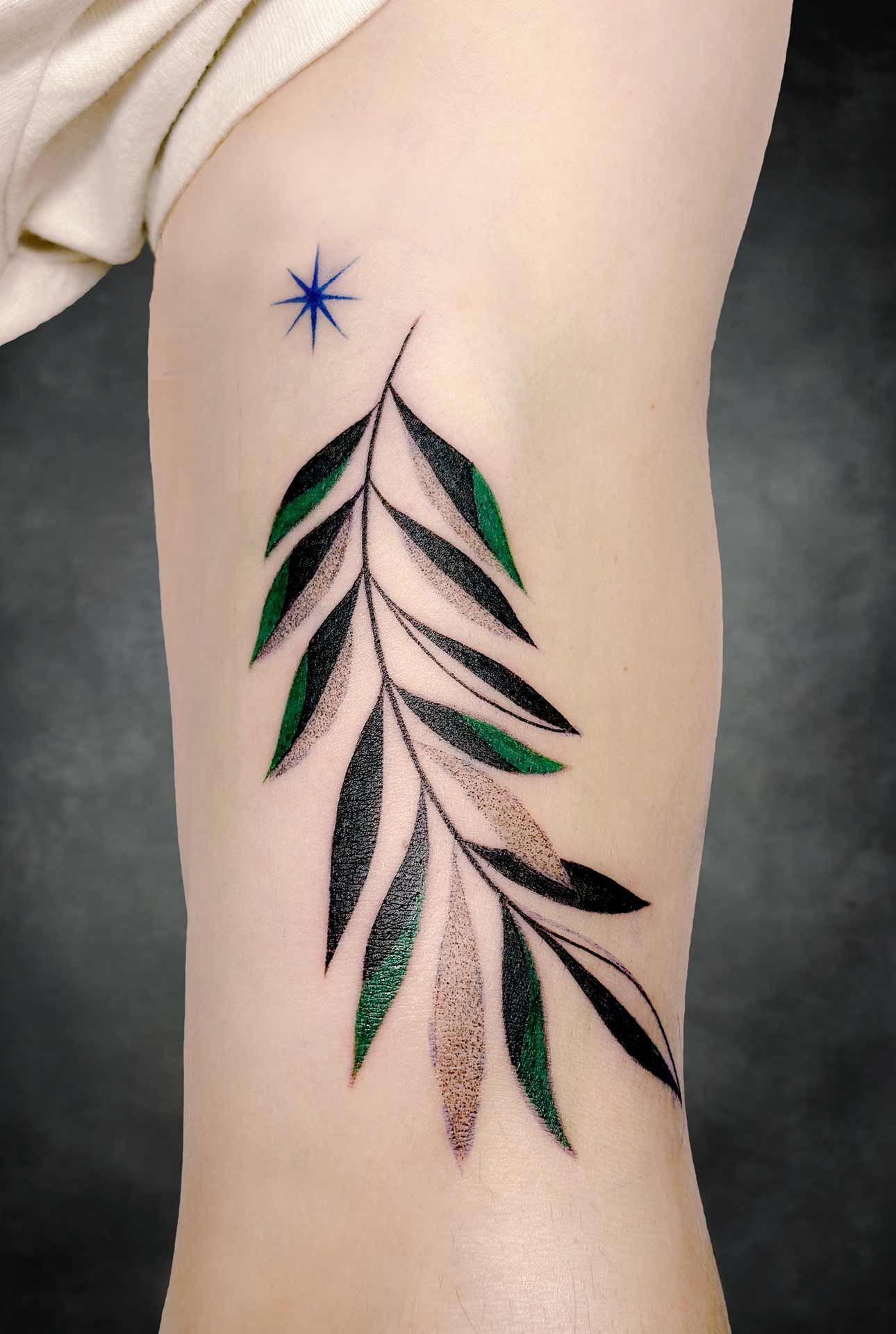 Une personne a un tatouage de feuille sur la jambe