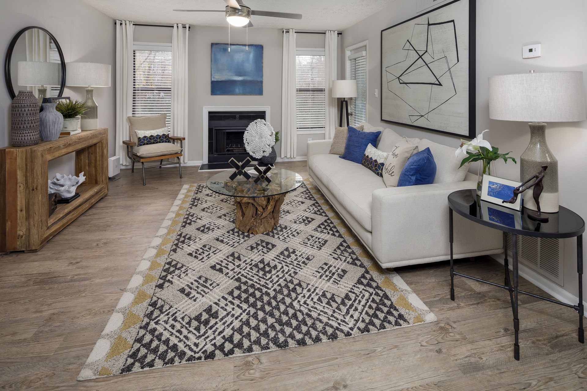 Living room with white sofa, patterned rug, fireplace, and artwork in a modern style.