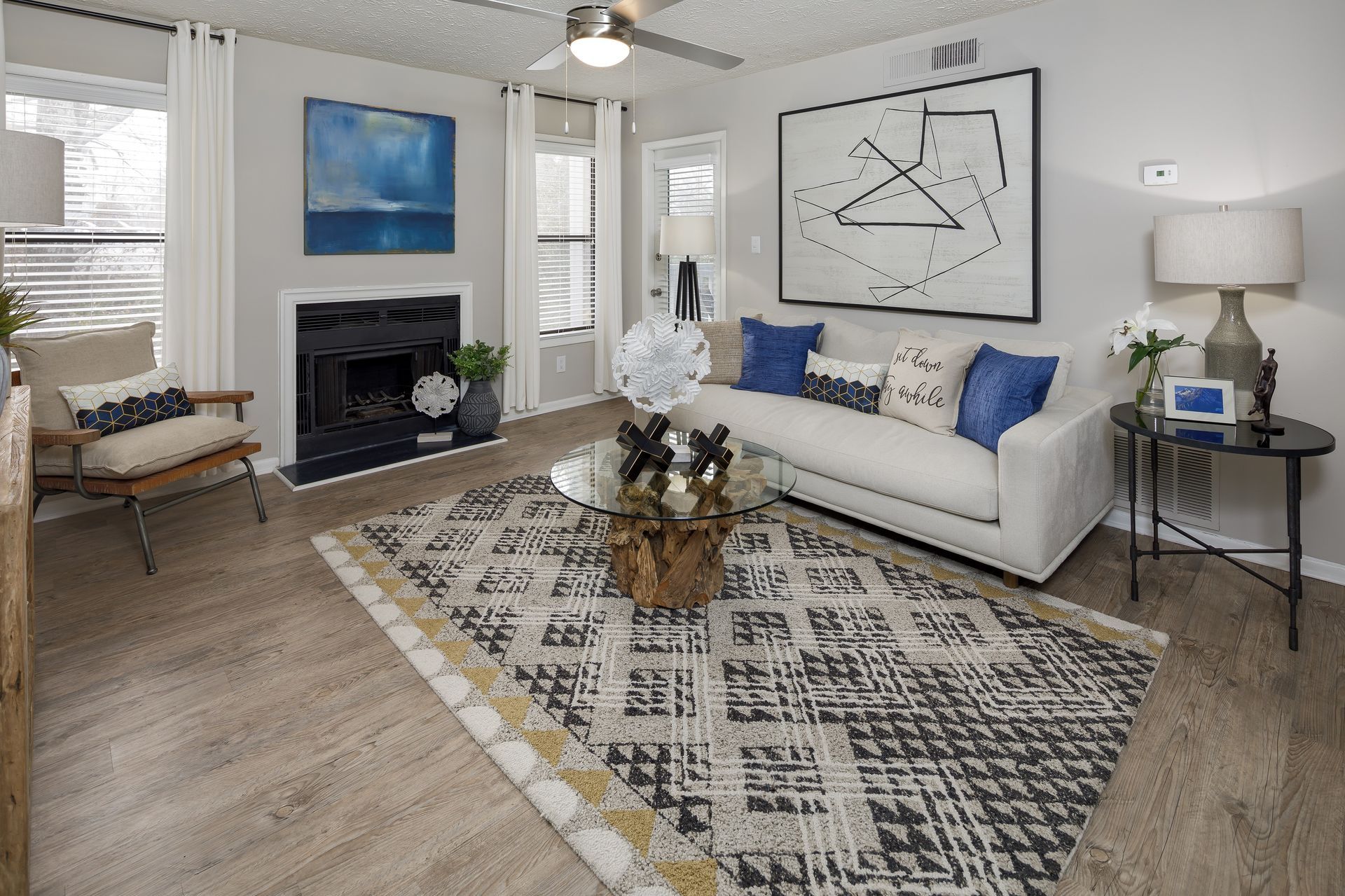 Living room with white couch, black fireplace, patterned rug, and blue and white accents.