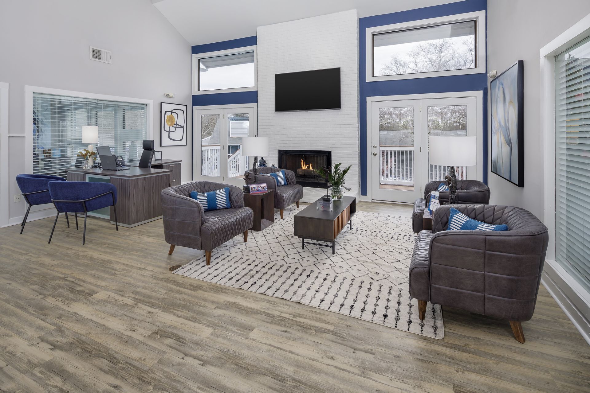 Living room with fireplace, blue accents, gray leather chairs, and a rug.