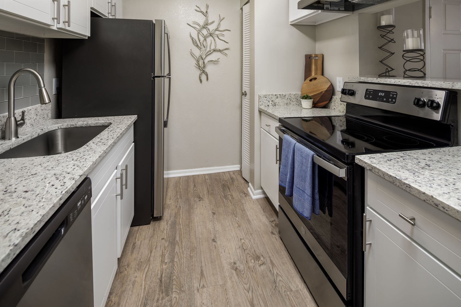 Modern kitchen with stainless steel appliances, white cabinets, and gray countertops.
