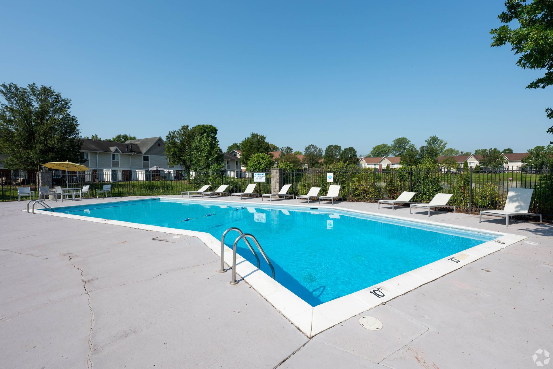 Swimming pool with lounge chairs, blue water, and a clear sky.