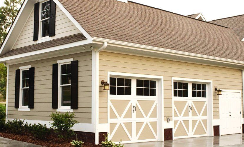 Tan two-car garage with a brown roof, white trim, and black shutters.