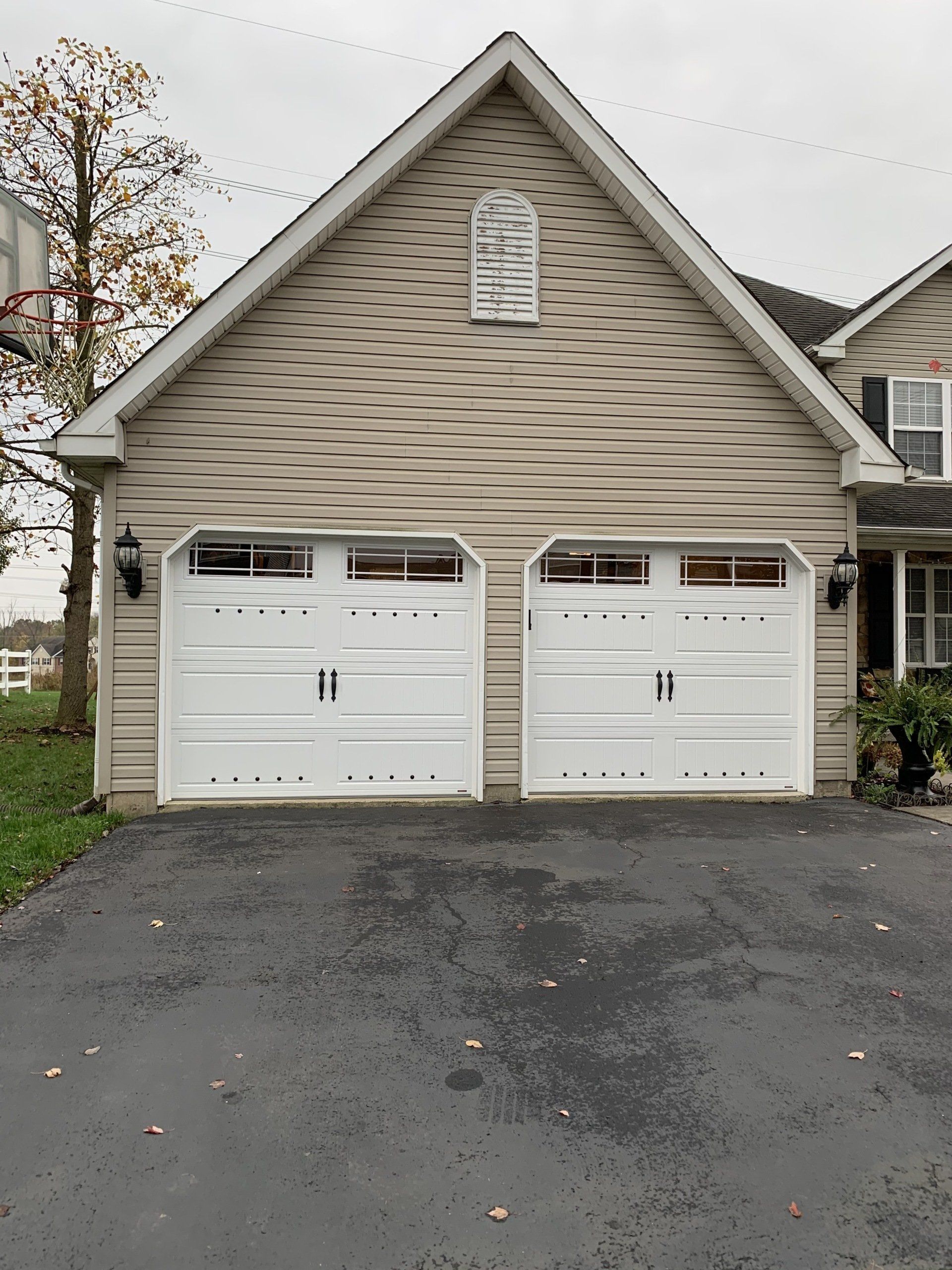 White garage doors with windows on a two-car garage under a peaked roof.