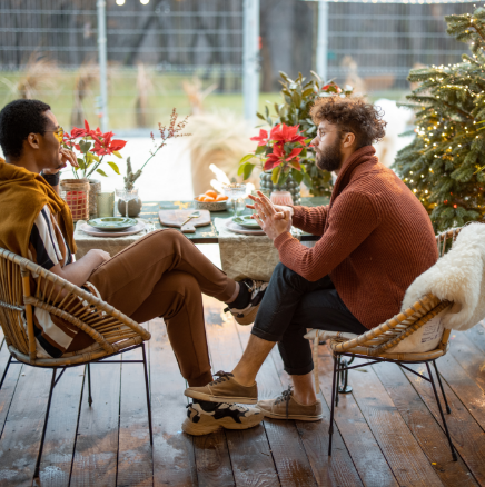Two men are sitting at a table with a christmas tree in the background.