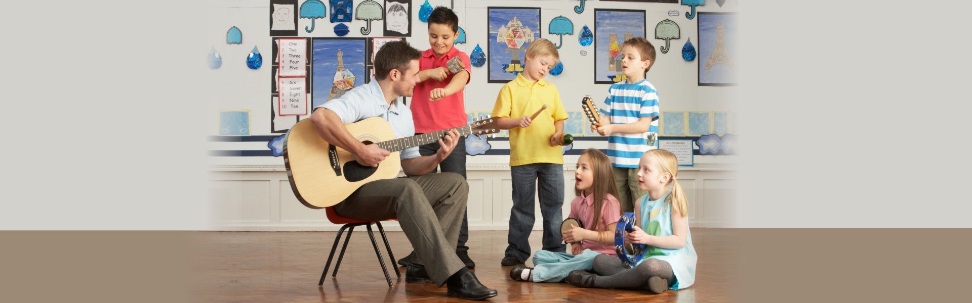 A man is playing a guitar in front of a group of children.