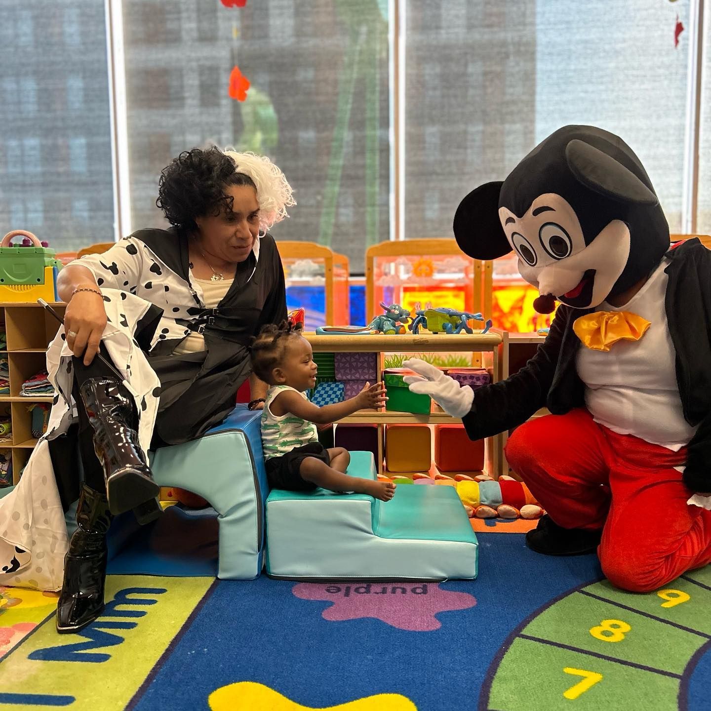 A woman in a dalmatian costume sits next to a mickey mouse mascot