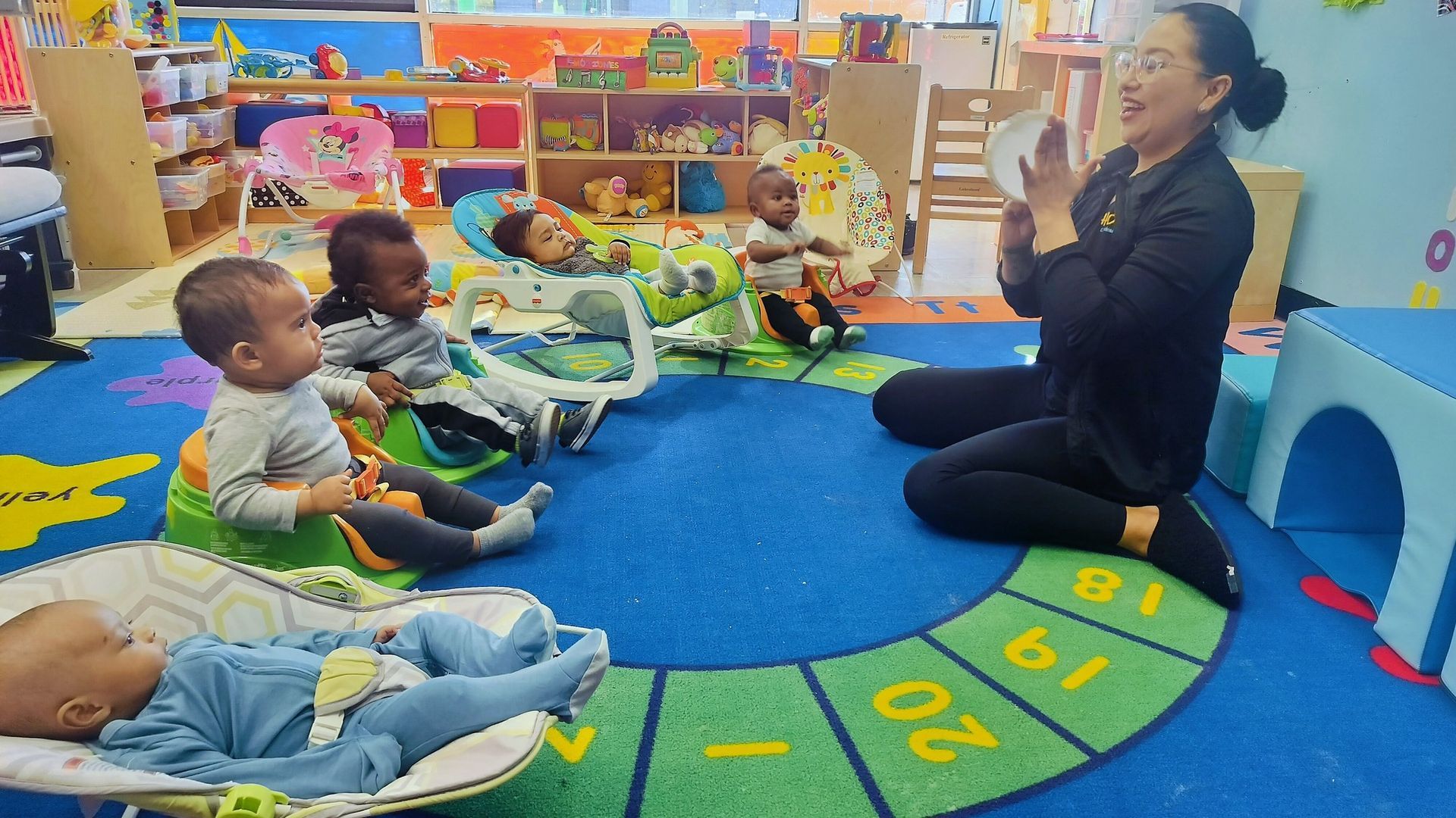 A woman is kneeling down in front of a group of babies