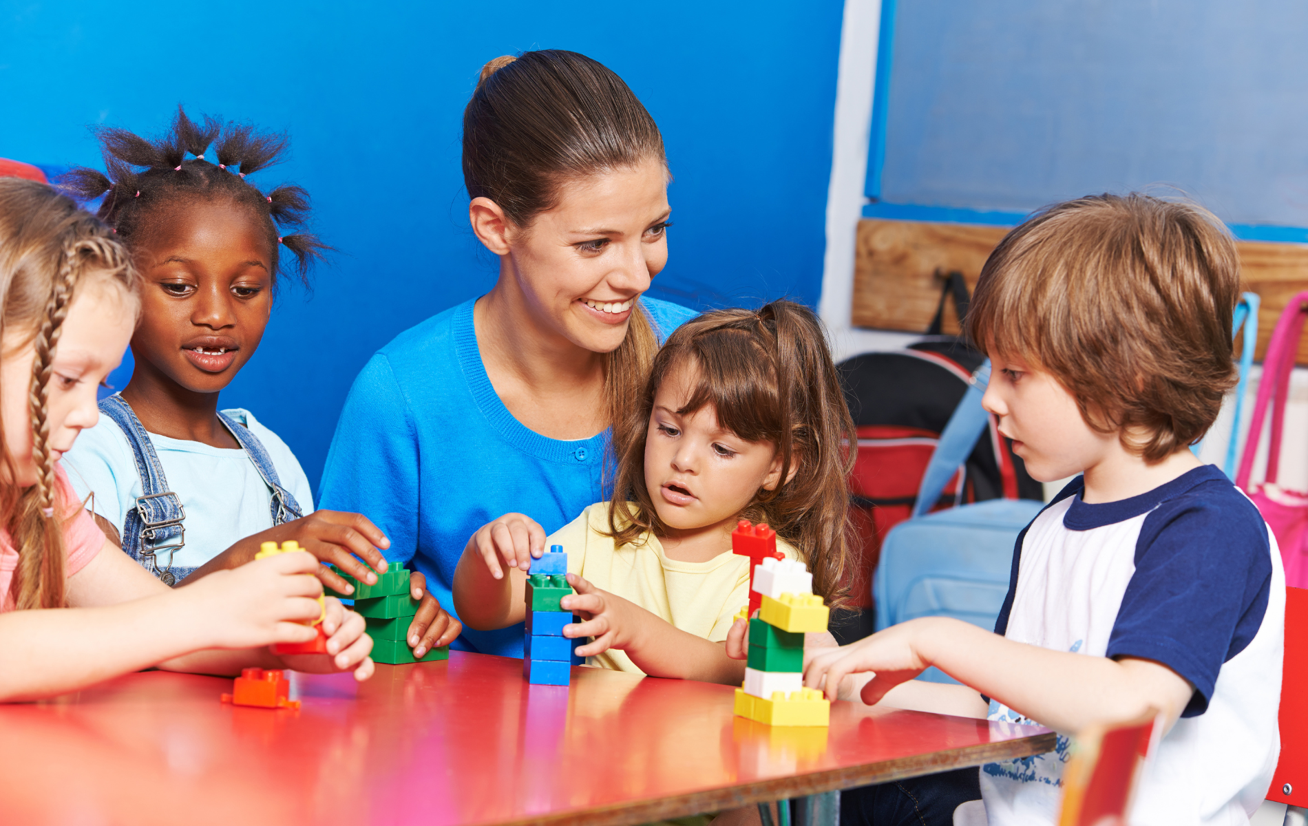 A group of children are sitting at a table playing with blocks.