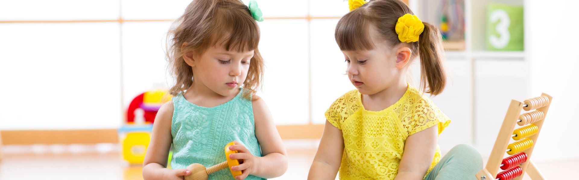 Two little girls are playing with toys in a room.
