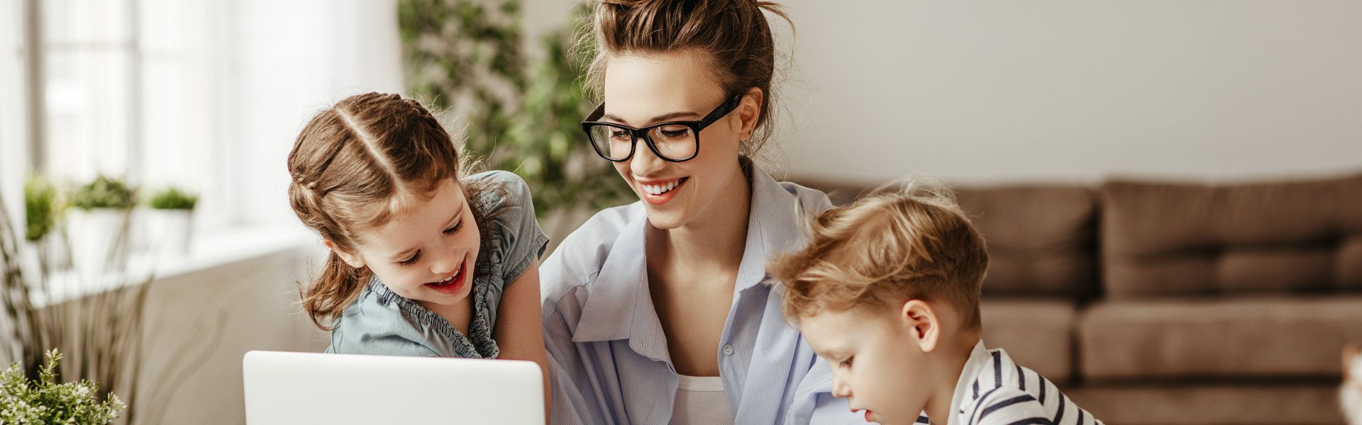 A woman and two children are looking at a laptop computer.