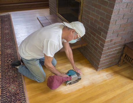 man refurbishing the wood floor