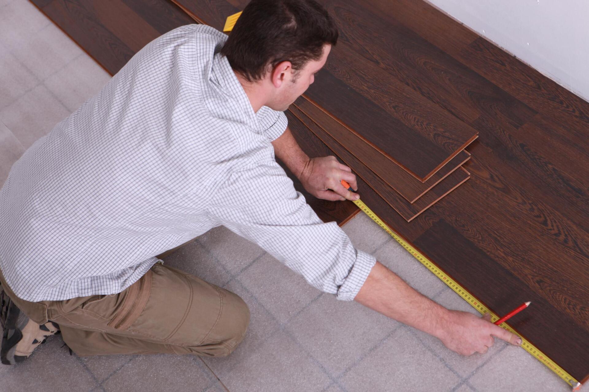 man measures the laminated wood planks