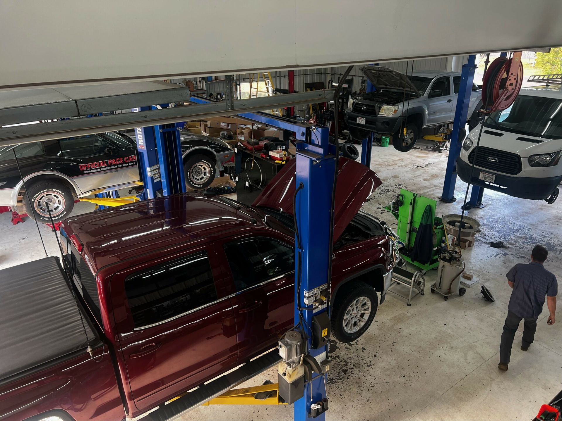 A red truck is sitting on a lift in a garage.