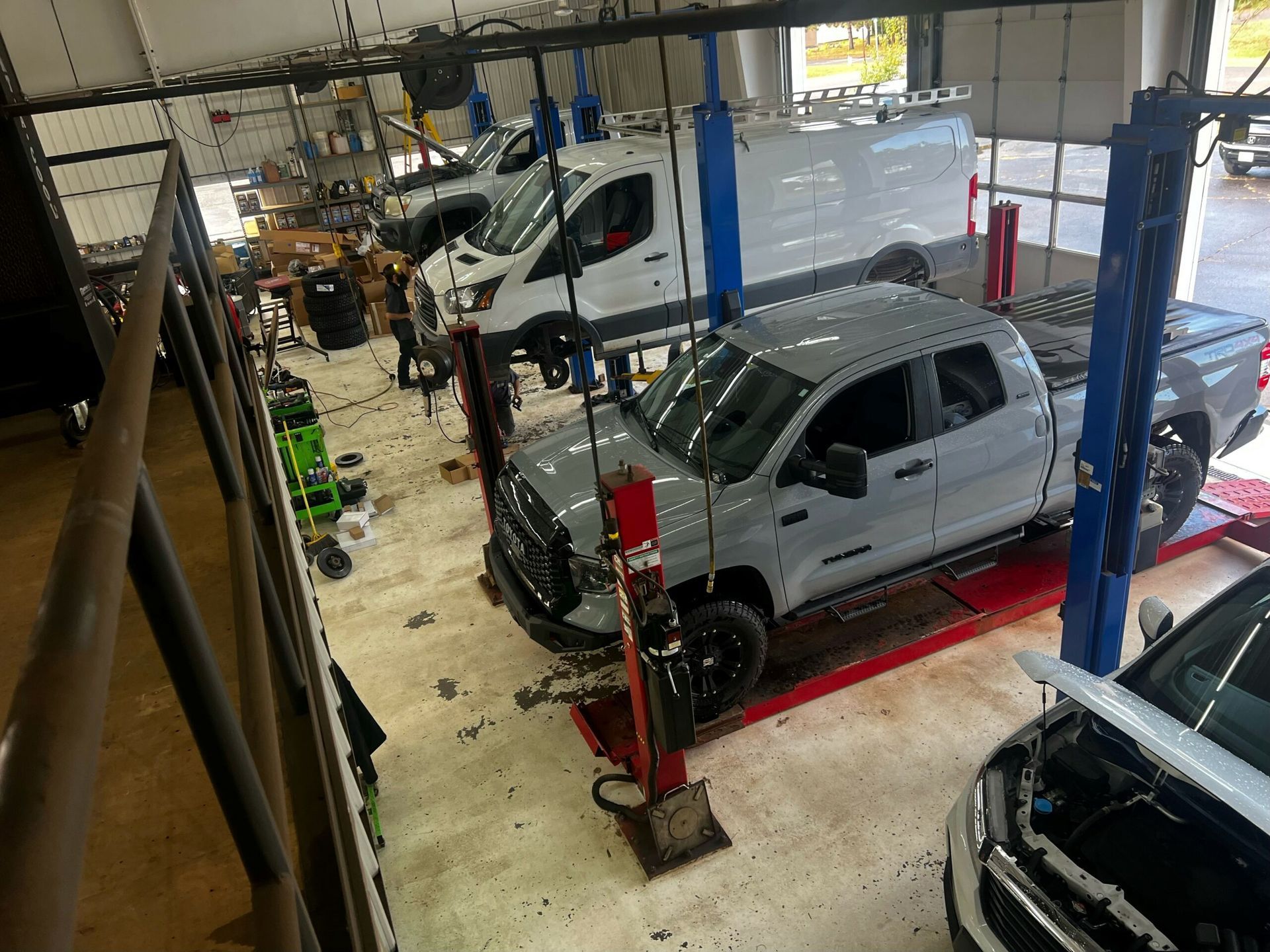 A row of cars are sitting on lifts in a garage.