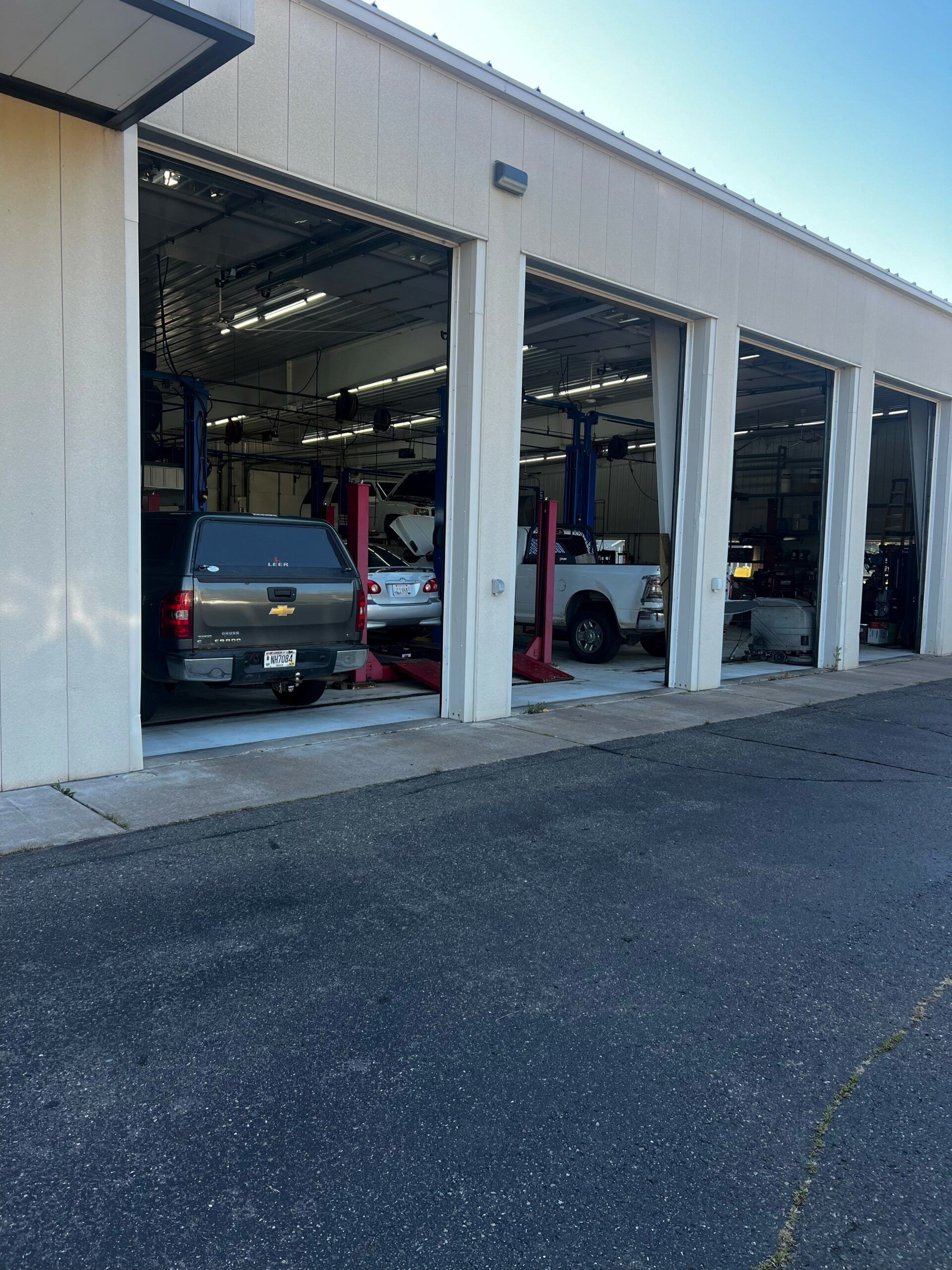 A row of cars are parked in a garage with the doors open