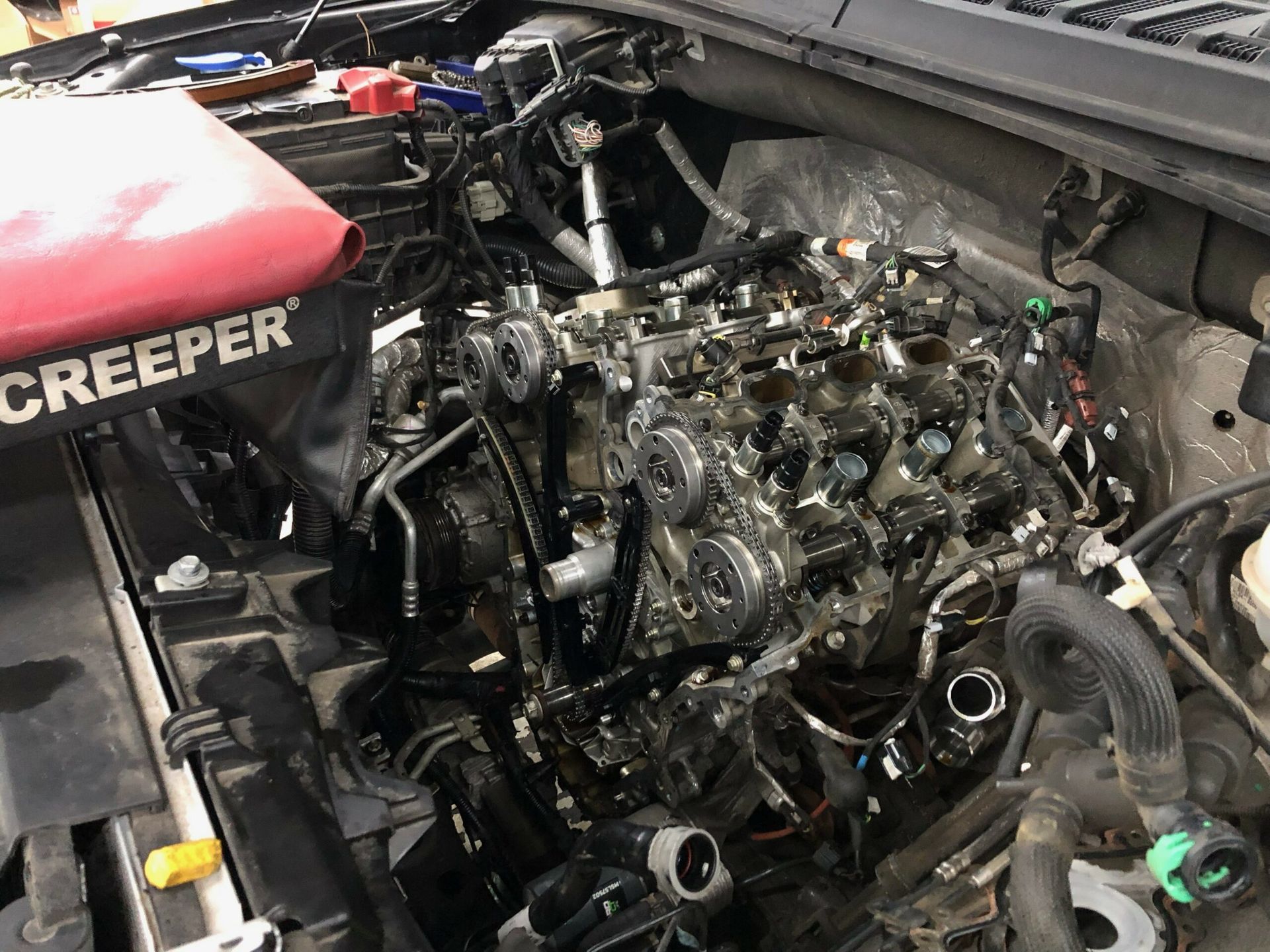 A close up of a car engine with a creeper bag on top of it.