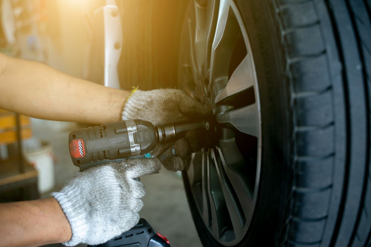 A person is changing a tire on a car with a wrench.