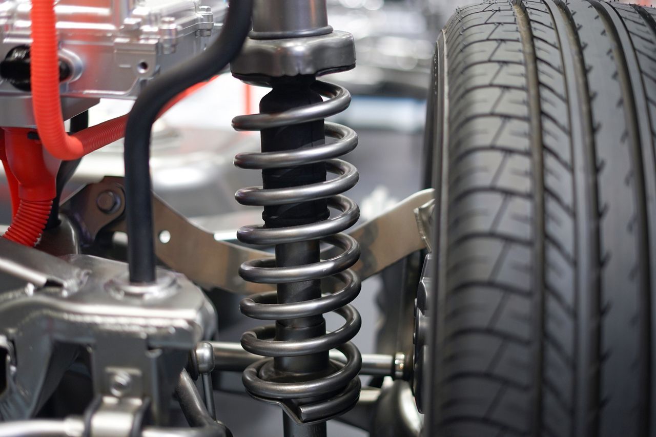 A close up of a car suspension with a tire in the background.
