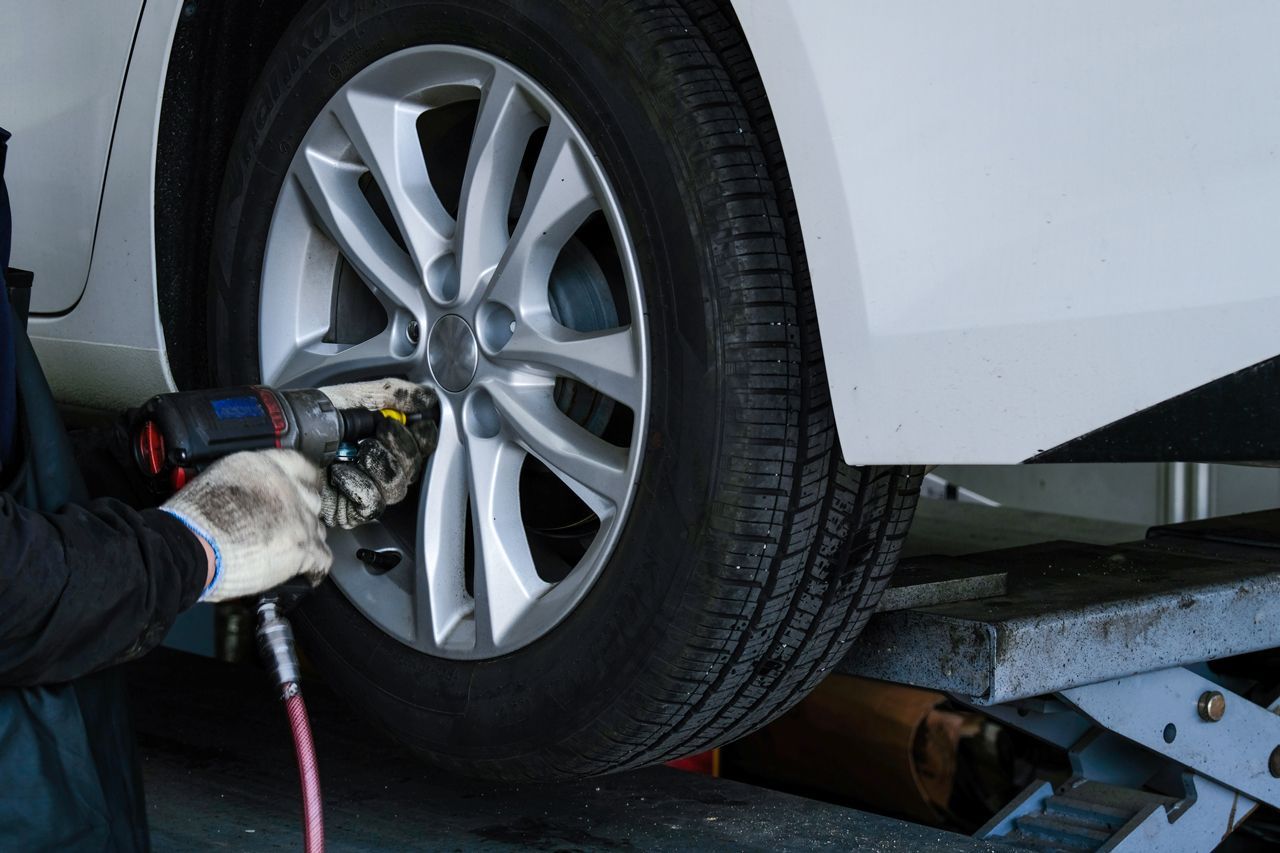 A person is changing a tire on a car with a wrench.