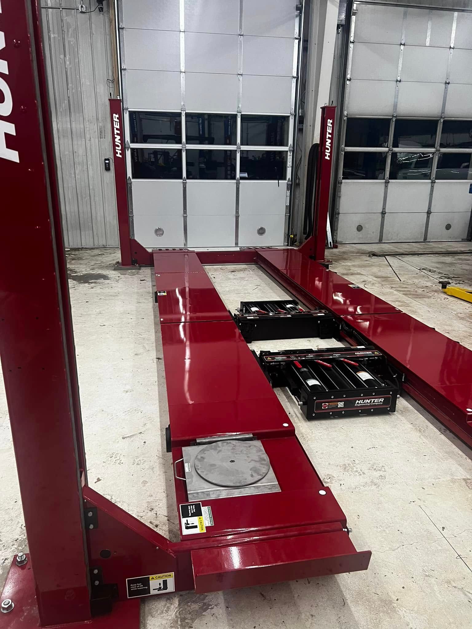 A red lift is sitting in a garage next to a garage door.