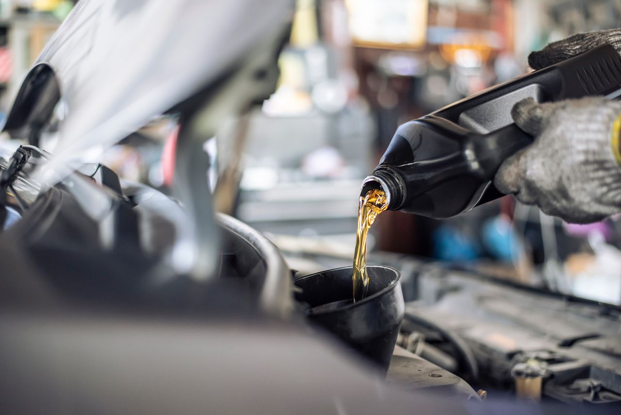 A person is pouring oil into a car engine.