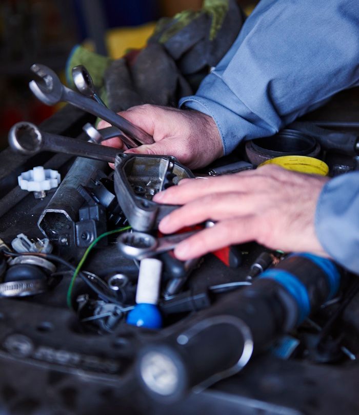 A man is working on a car engine with a bunch of tools