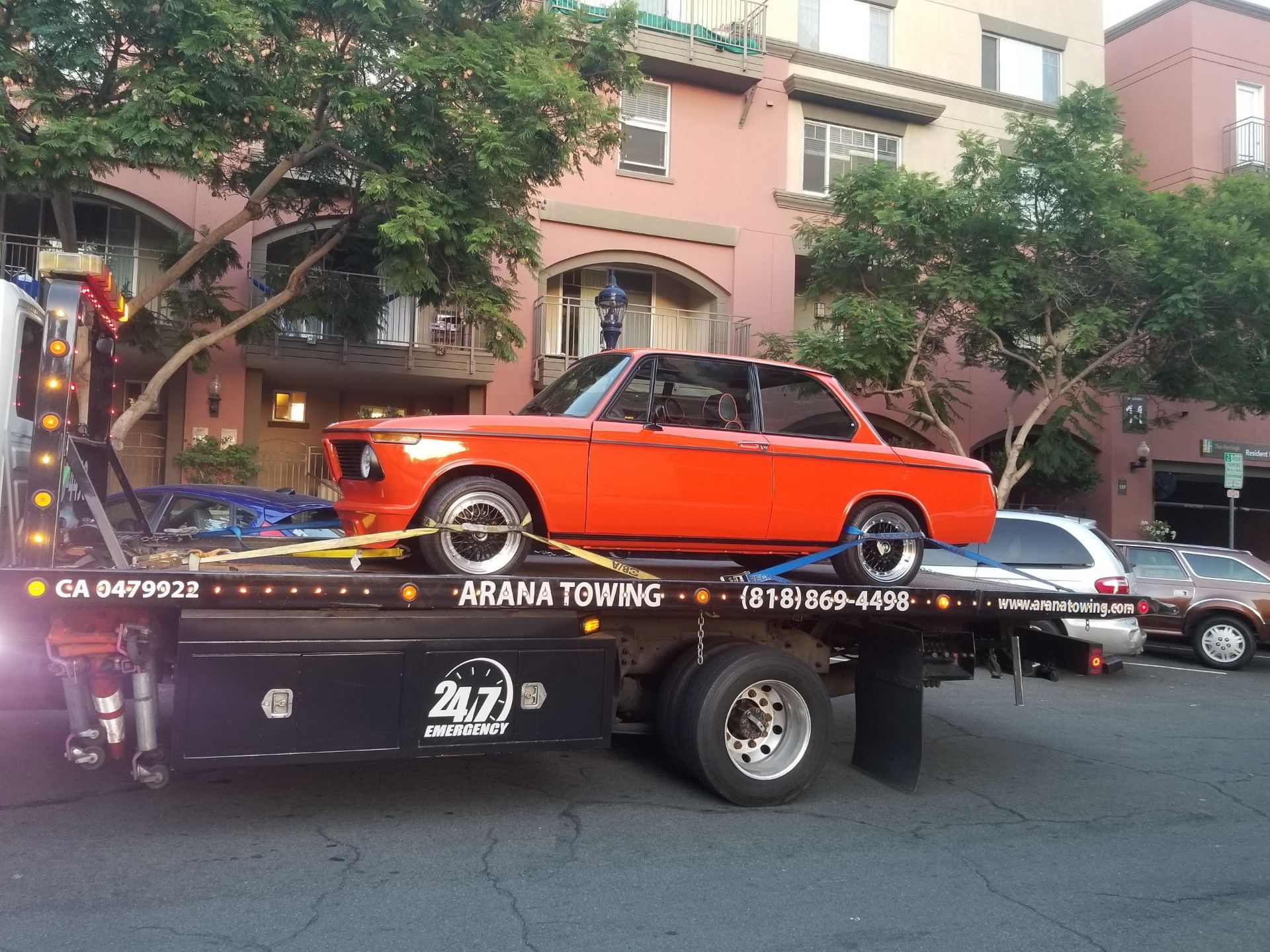 A red car is on the back of a tow truck