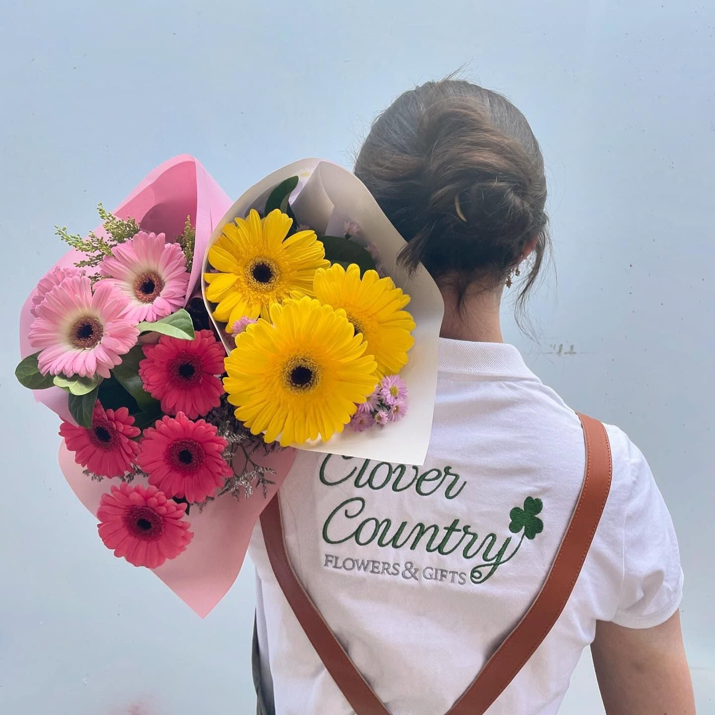 A Woman Wearing A Clover Country Shirt Is Holding A Bouquet Of Flowers — Clover Country Flowers and Gifts In Pittsworth, QLD