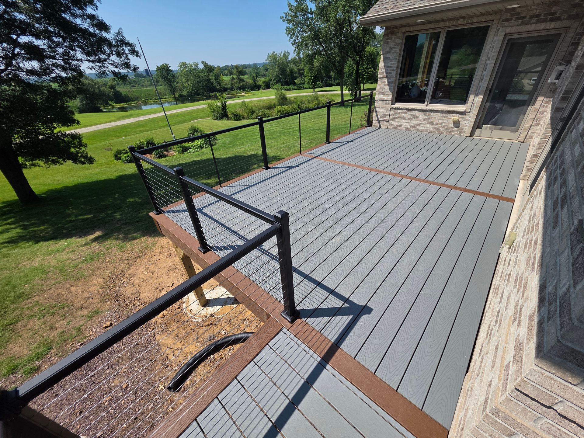 Gray composite deck with black railing and brown accents, overlooking a golf course.