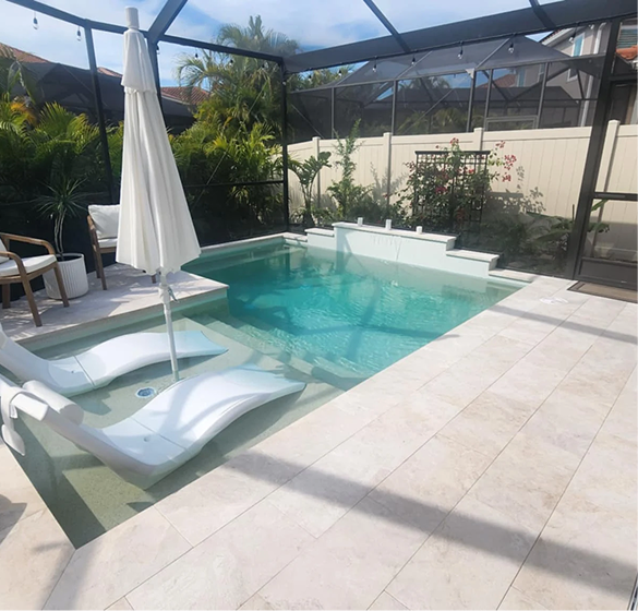 Outdoor pool with chaise loungers, white umbrella, and surrounding patio.