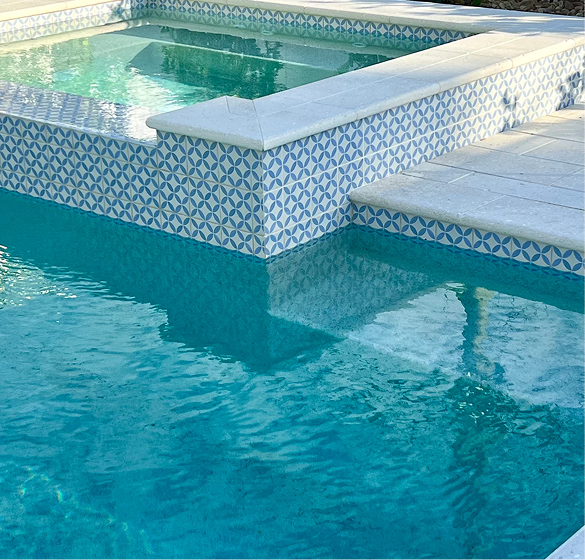 A rectangular pool with turquoise water, a connected spa, and a house in the background. Sunny day.
