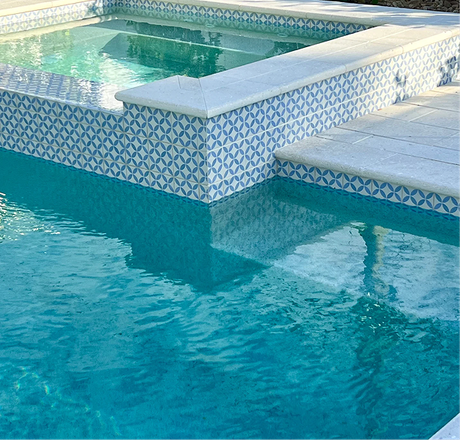 A rectangular pool with turquoise water, a connected spa, and a house in the background. Sunny day.