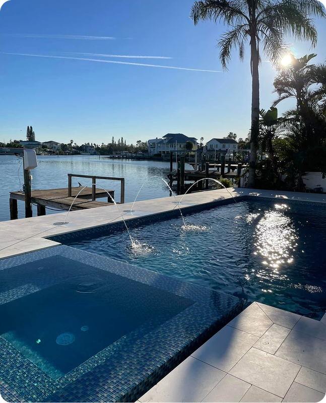 Poolside view with turquoise water, dock, palms, and a person sunbathing.