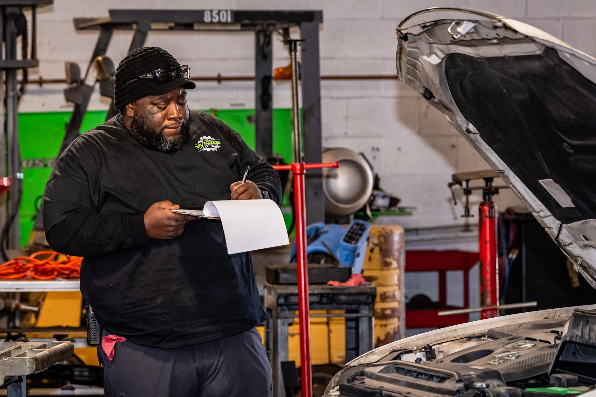 A man is standing in a garage next to a truck.