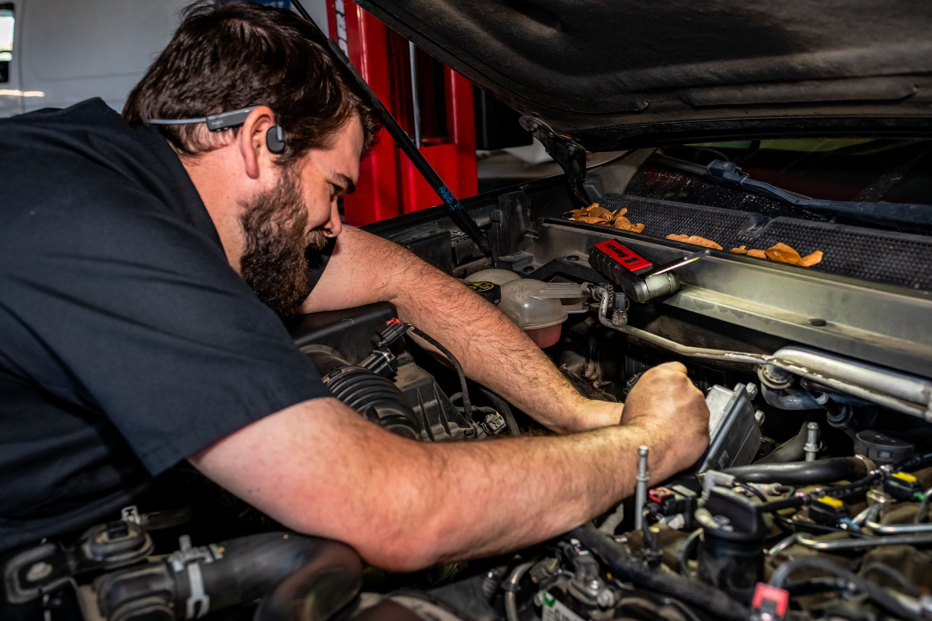 Two men are working on a car engine in a garage.