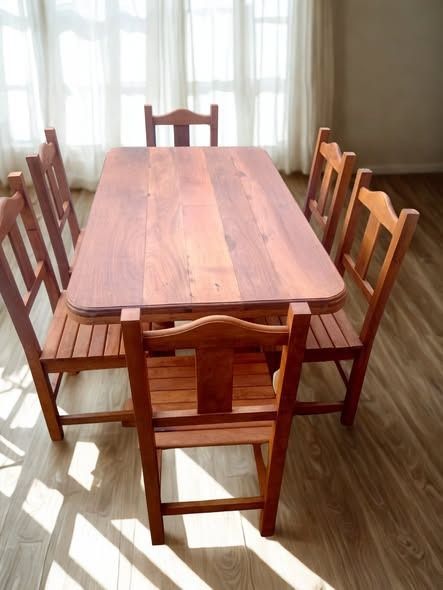 Mesa de comedor de madera con seis sillas a juego en una habitación iluminada por el sol.