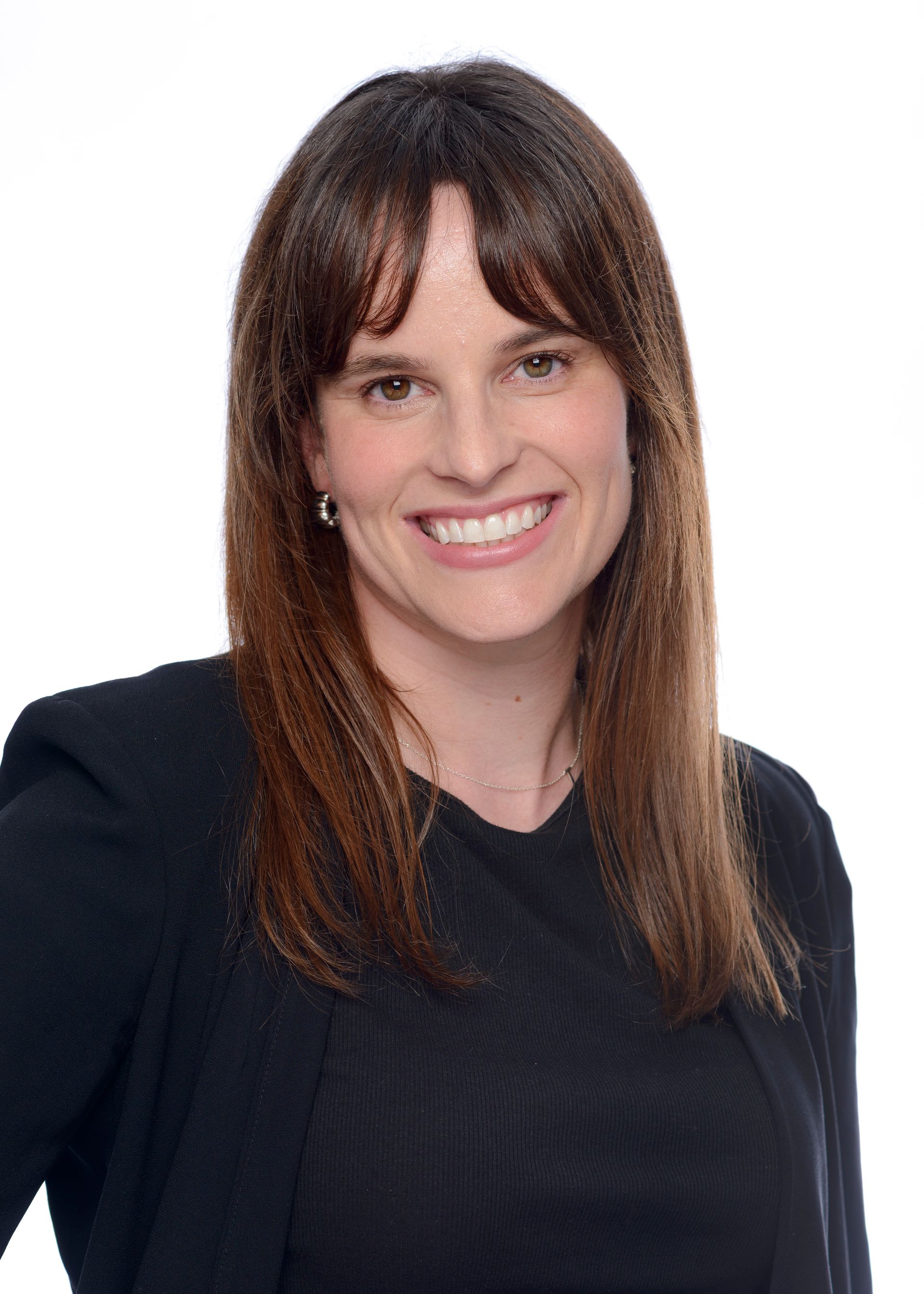 A woman wearing a brown jacket and earrings is smiling for the camera.
