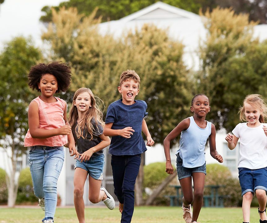 A group of children are running in a park.