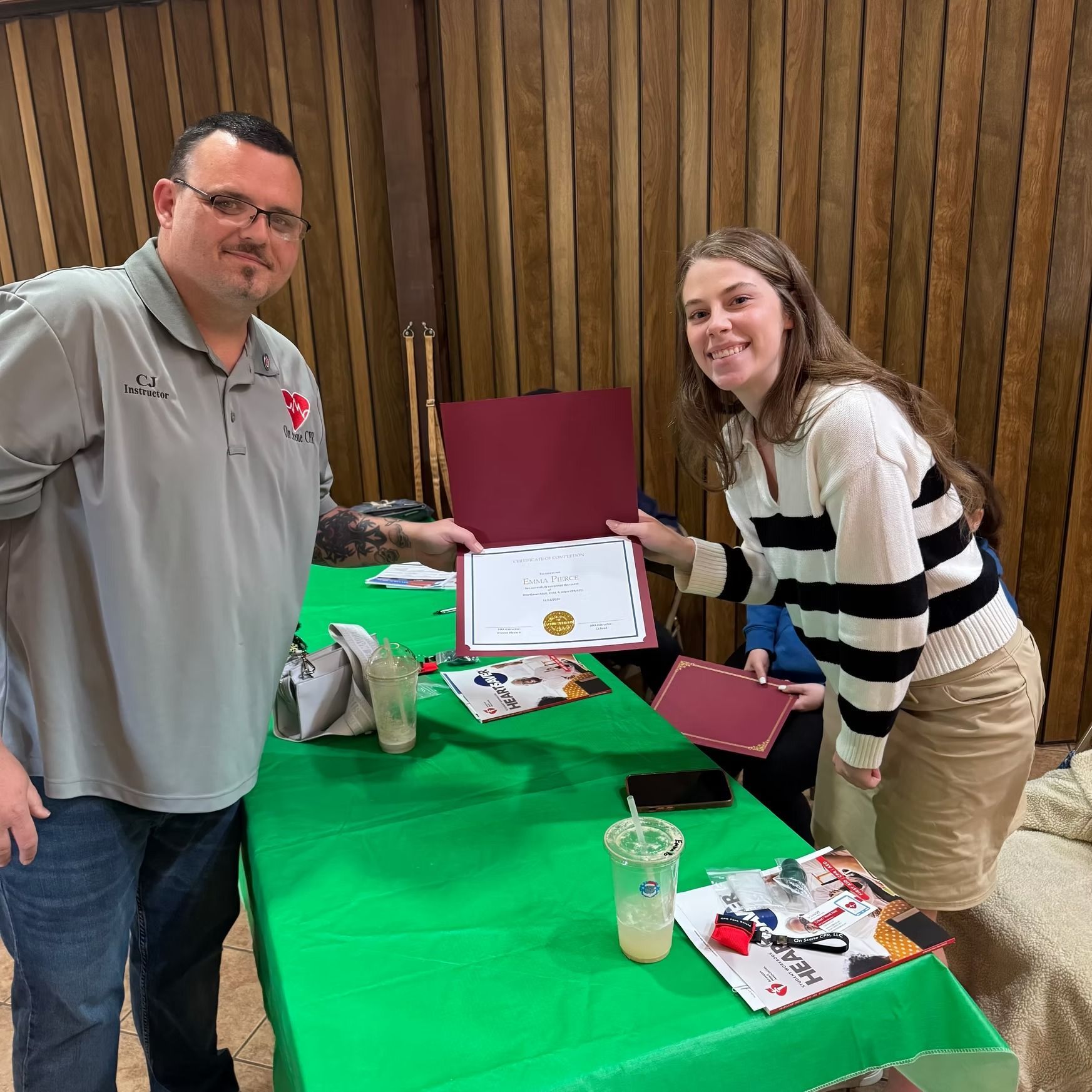 A man and a woman are standing next to each other at a table holding a certificate.