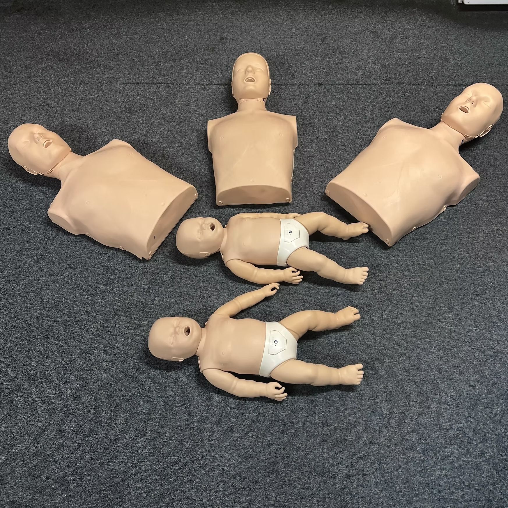 A group of baby mannequins are laying on the floor