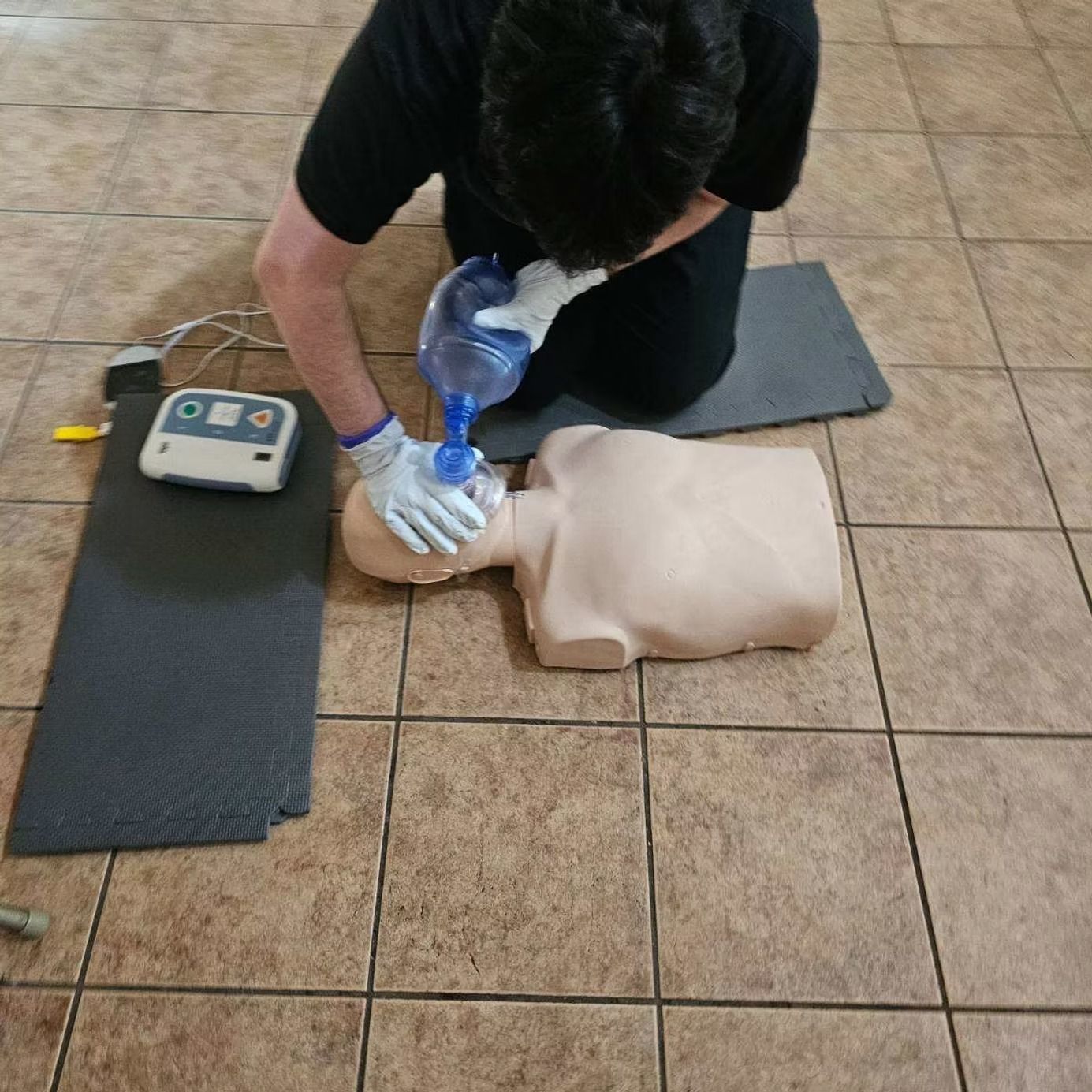 A man is kneeling down with a mask on a mannequin