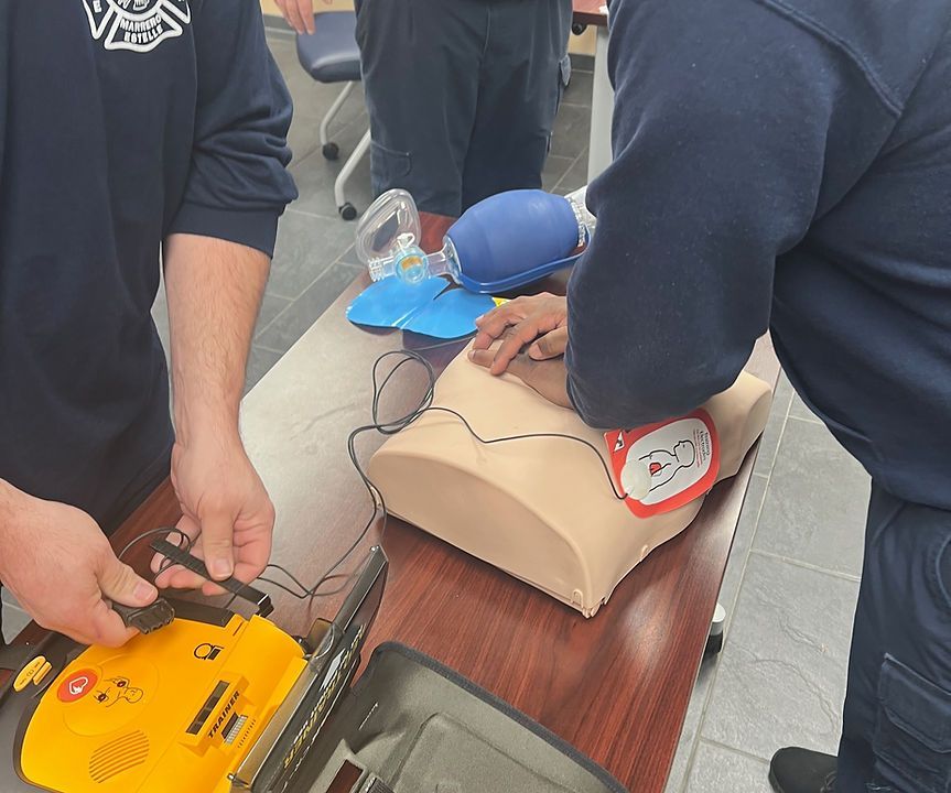 A man is using a defibrillator on a mannequin.