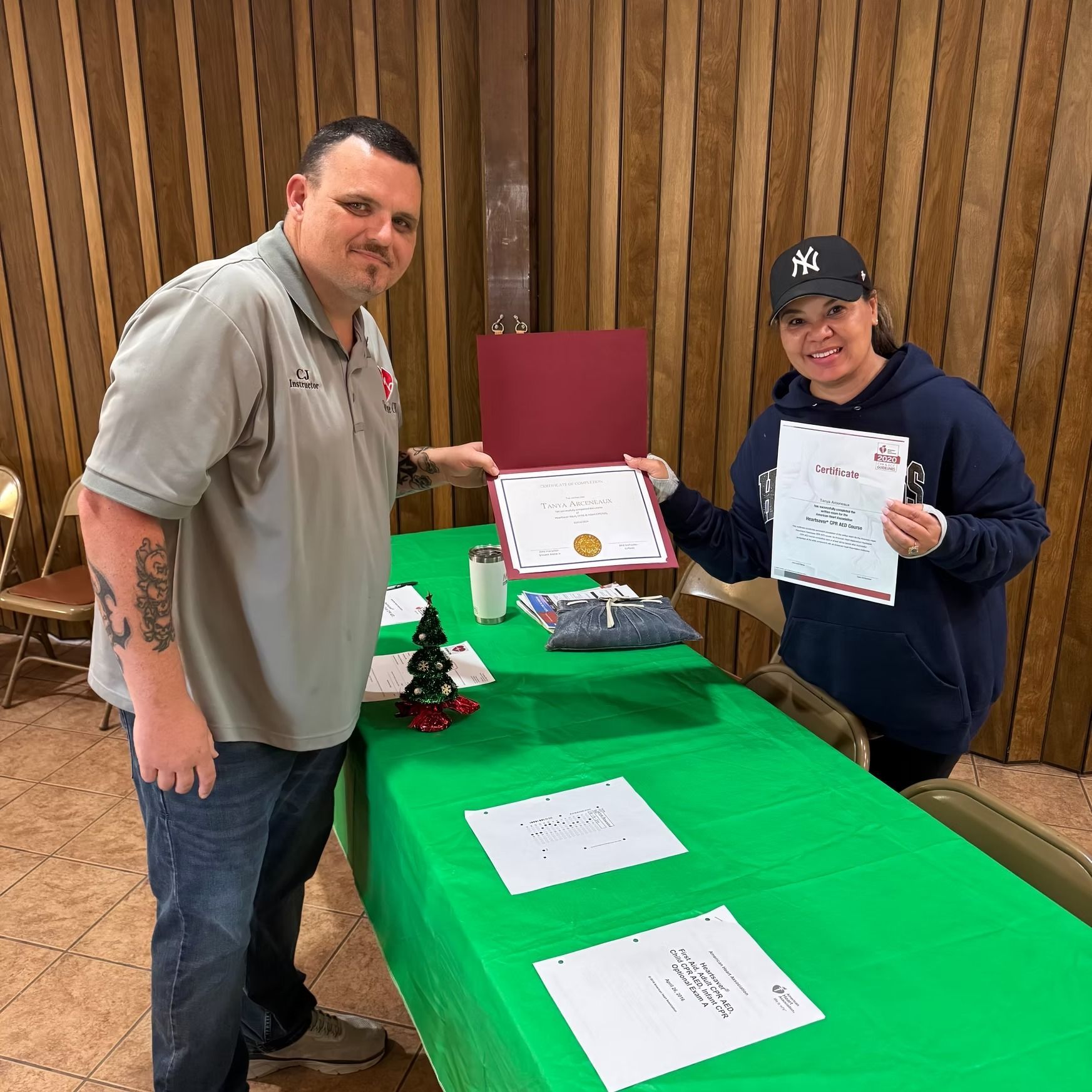 A man and a woman are standing next to each other at a table holding papers.