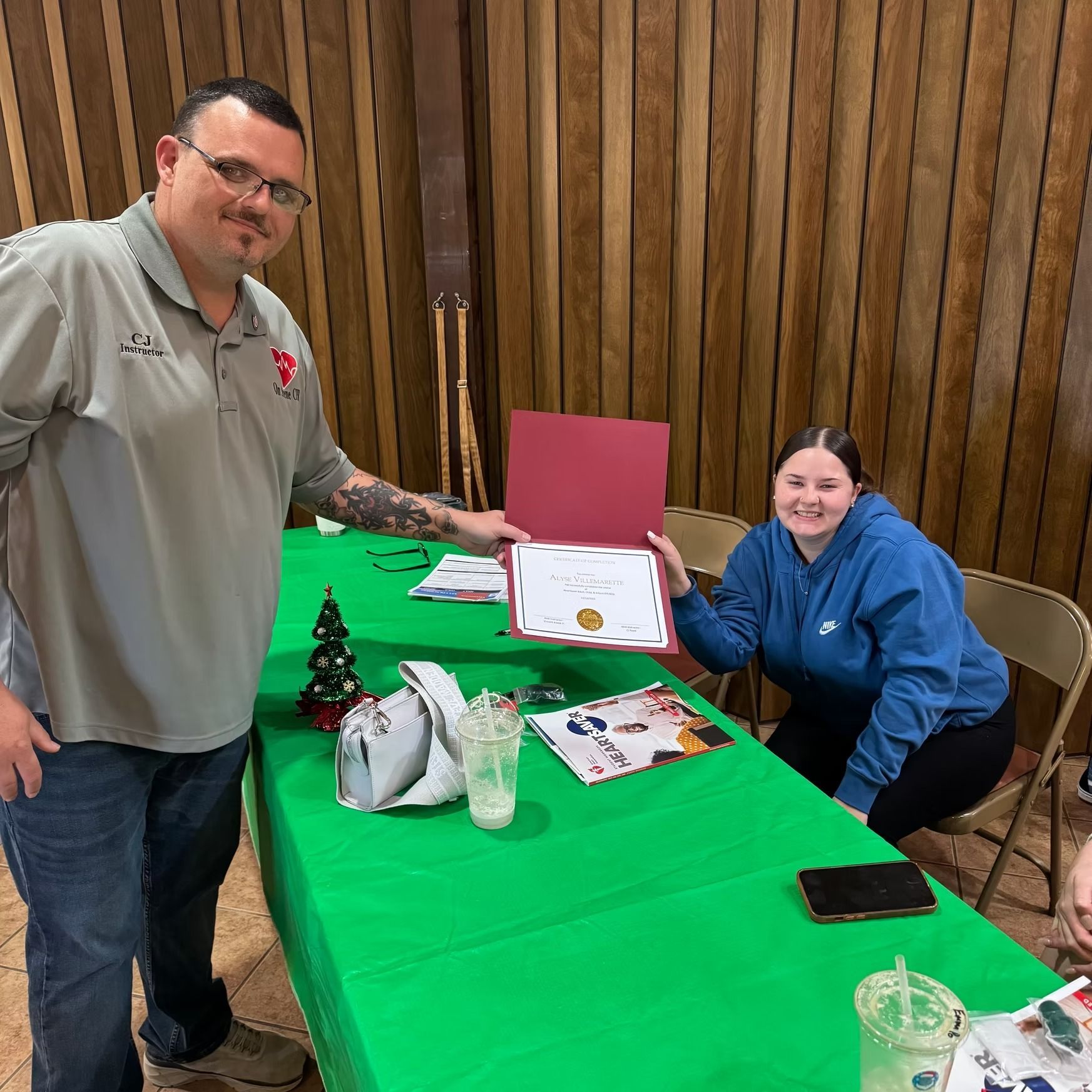 A man and a woman are sitting at a table holding a certificate.