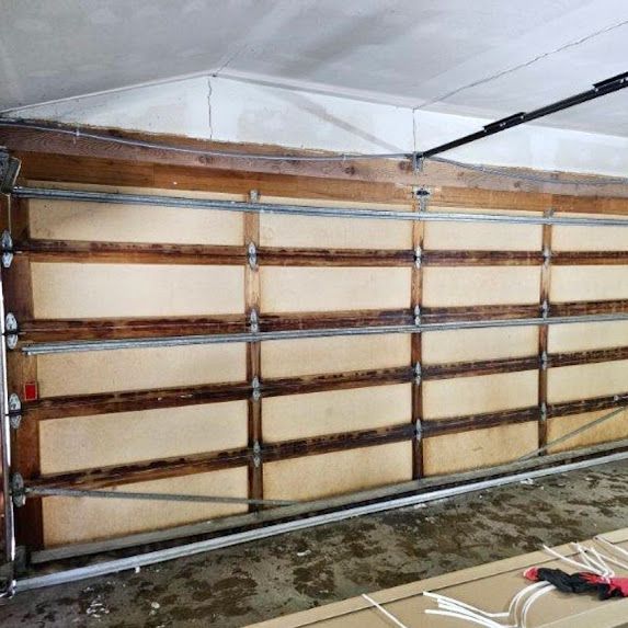 A large wooden garage door is open in a garage.