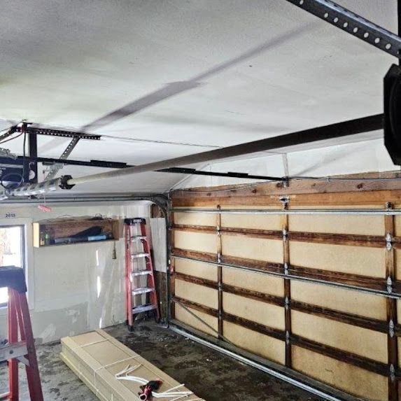 A garage with a ladder and a garage door open