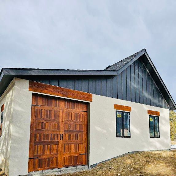 A small white house with a wooden garage door and windows.
