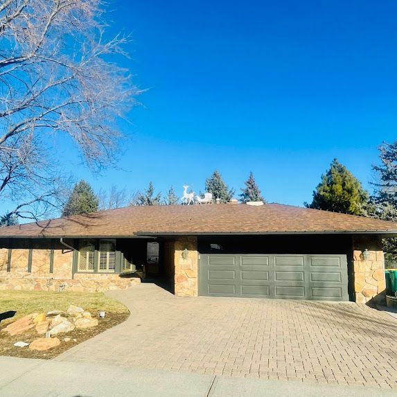 A house with a brick driveway and a brown roof