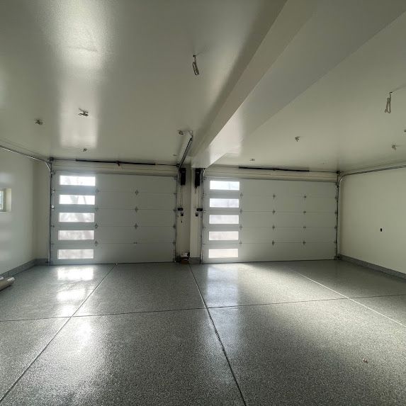 An empty garage with a white garage door and a gray floor